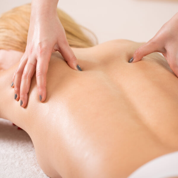 Therapist pressing tight muscles on woman's back